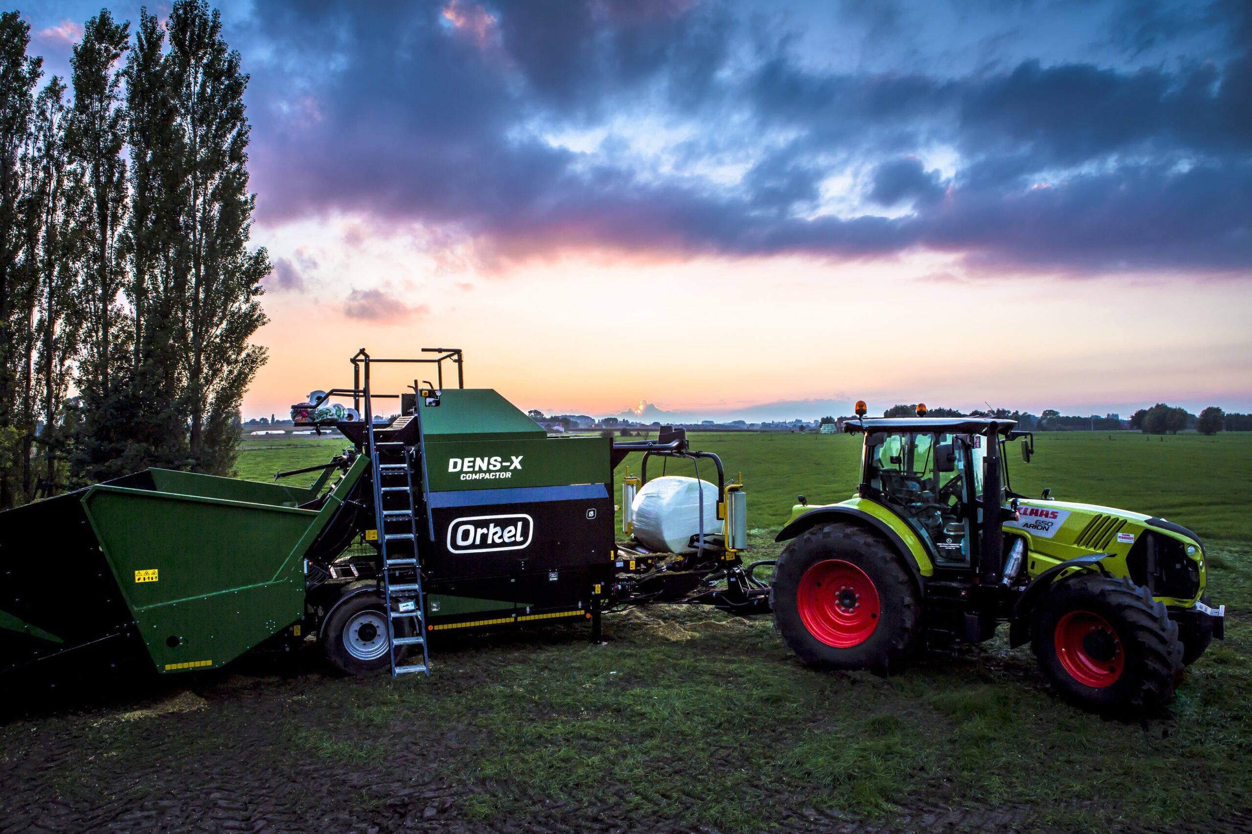 Ein Dens-X Verdichter und ein Traktor, mit grünem Gras und rosa Himmel sowie schweren Wolken.
