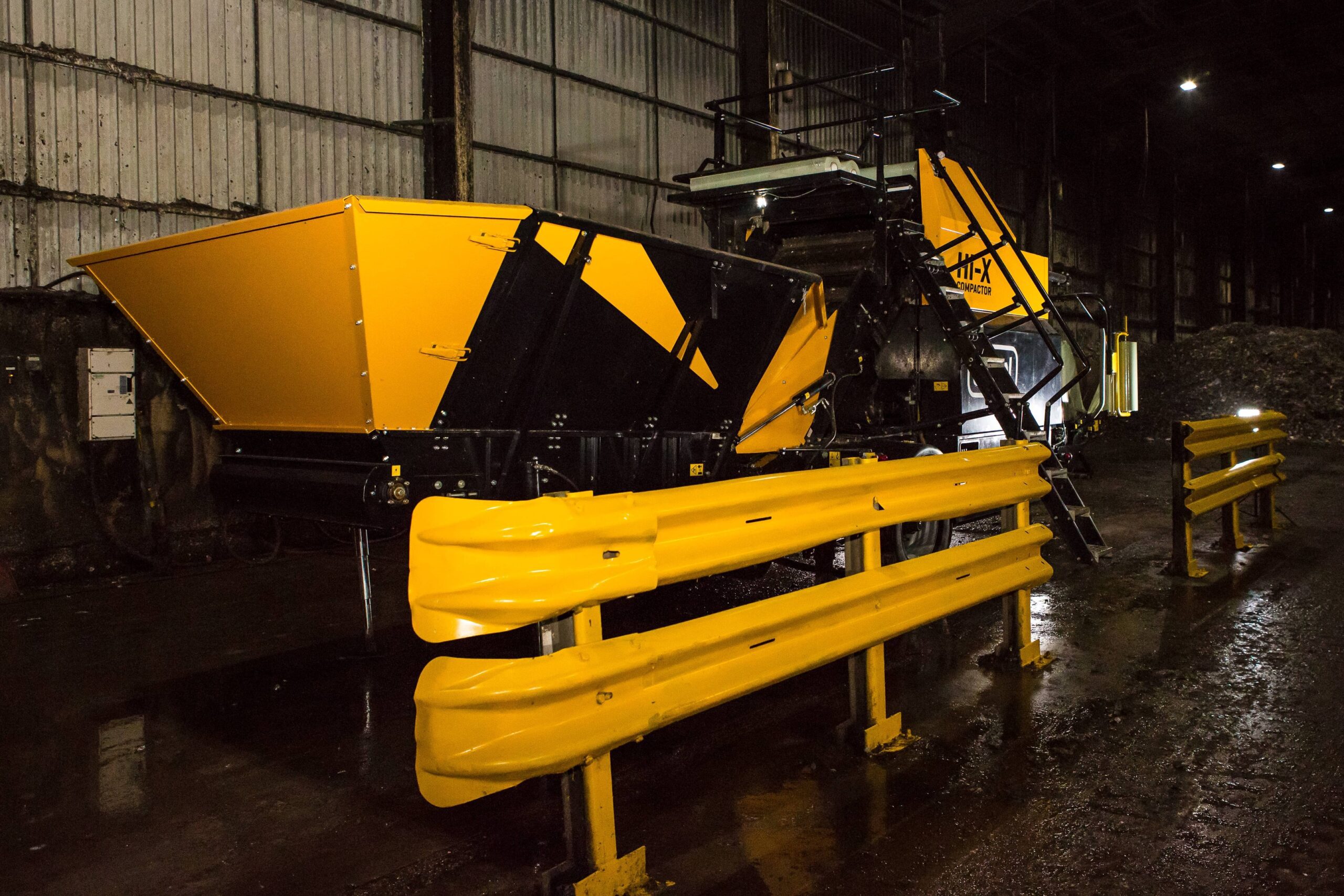 The feeding table of a Hi-X compactor with yellow railing between the machine and the camera.
