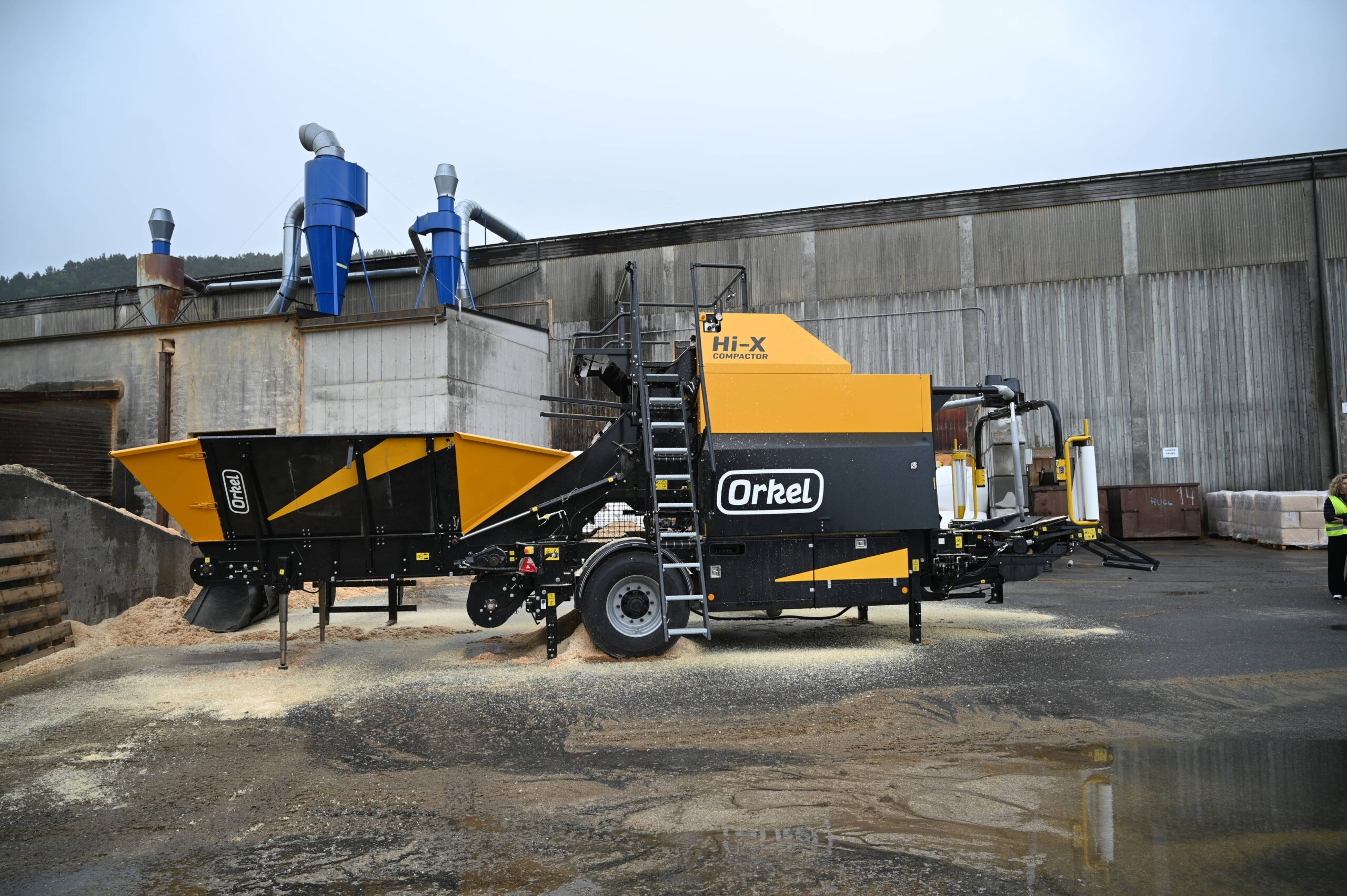 A Hi-X compactor on a concrete flooring with a concrete building and grey skies in the background.