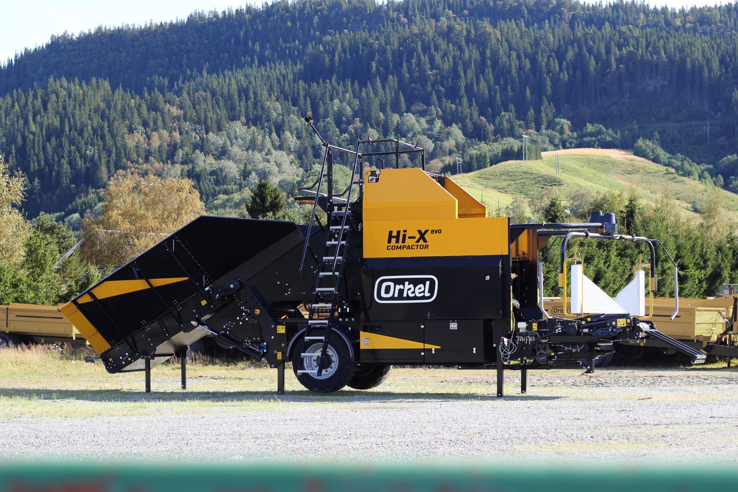 Side shot of a Hi-X evo, with green pine trees and hills in the background.