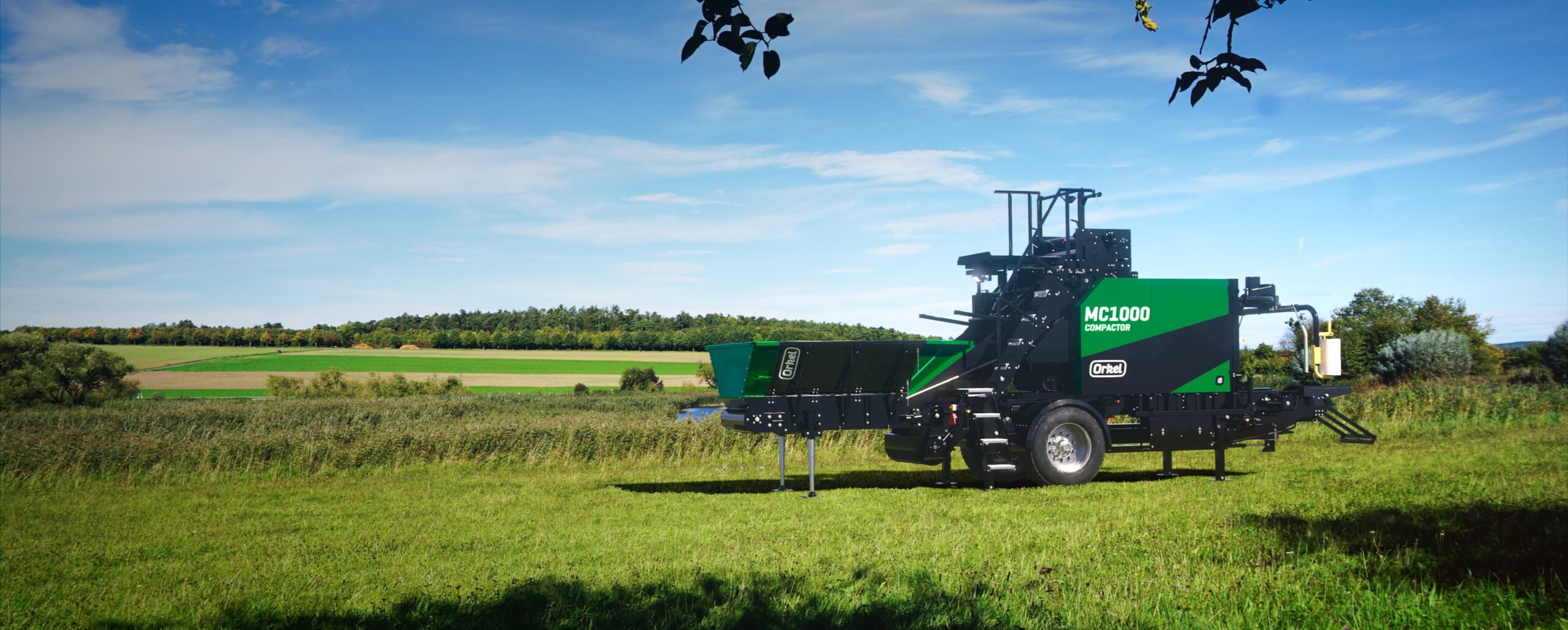 An MP1000 compactor in a field, with green grass flooring and blue skies.
