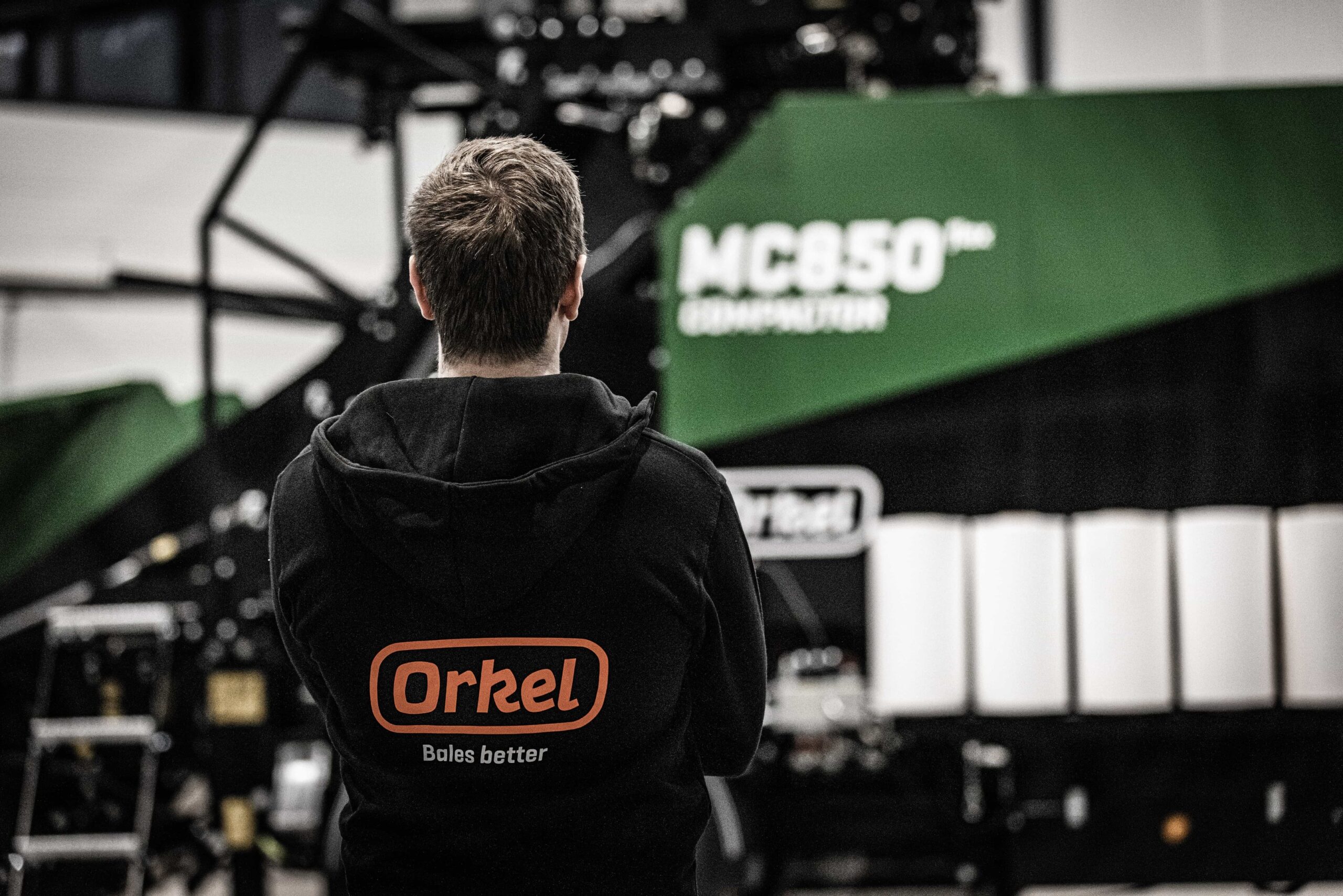 A person wearing an Orkel hoodie standing in front of an MC850 flex.