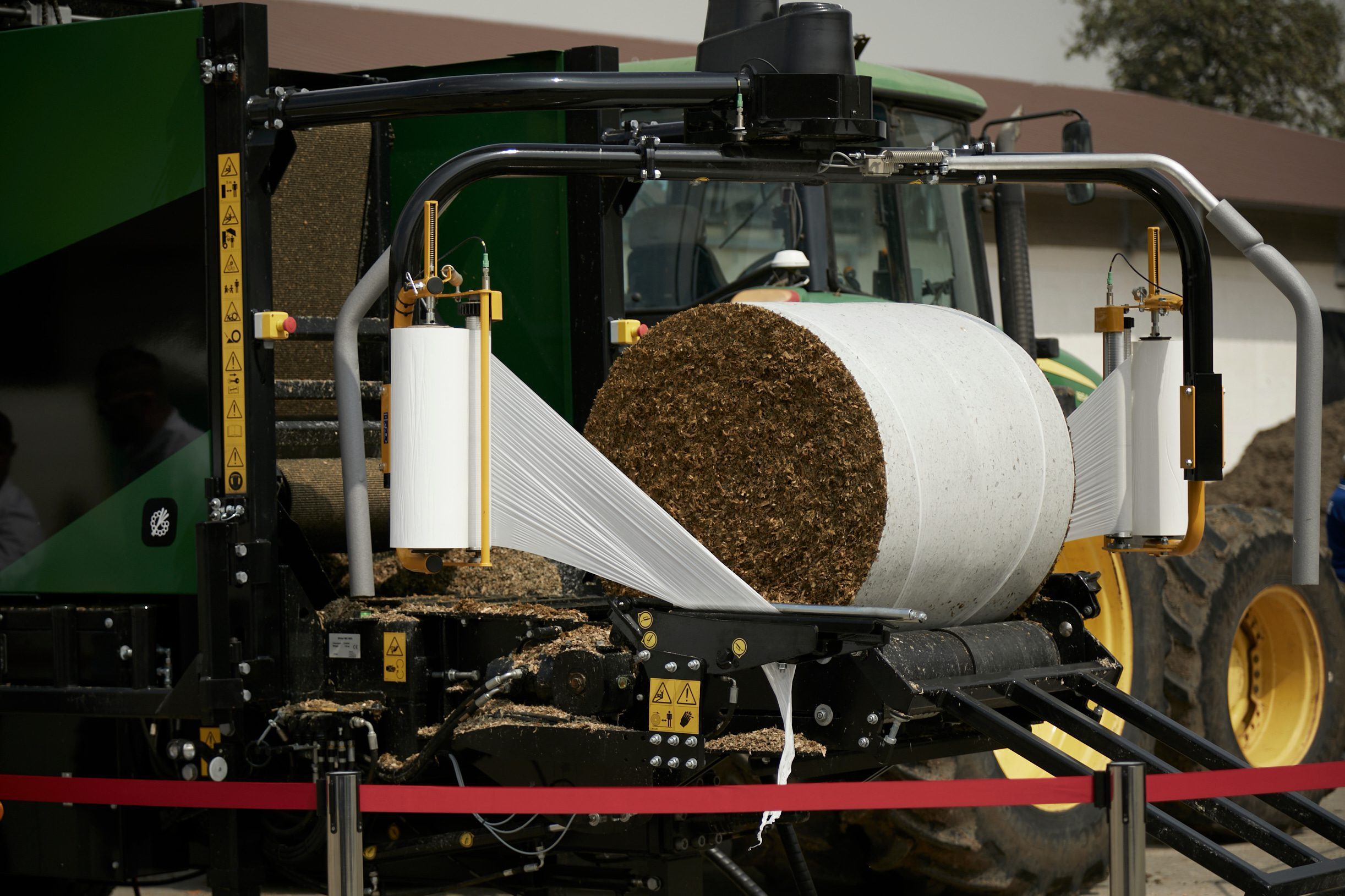 A half-wrapped bale with brown grassy material on a wrapping table.
