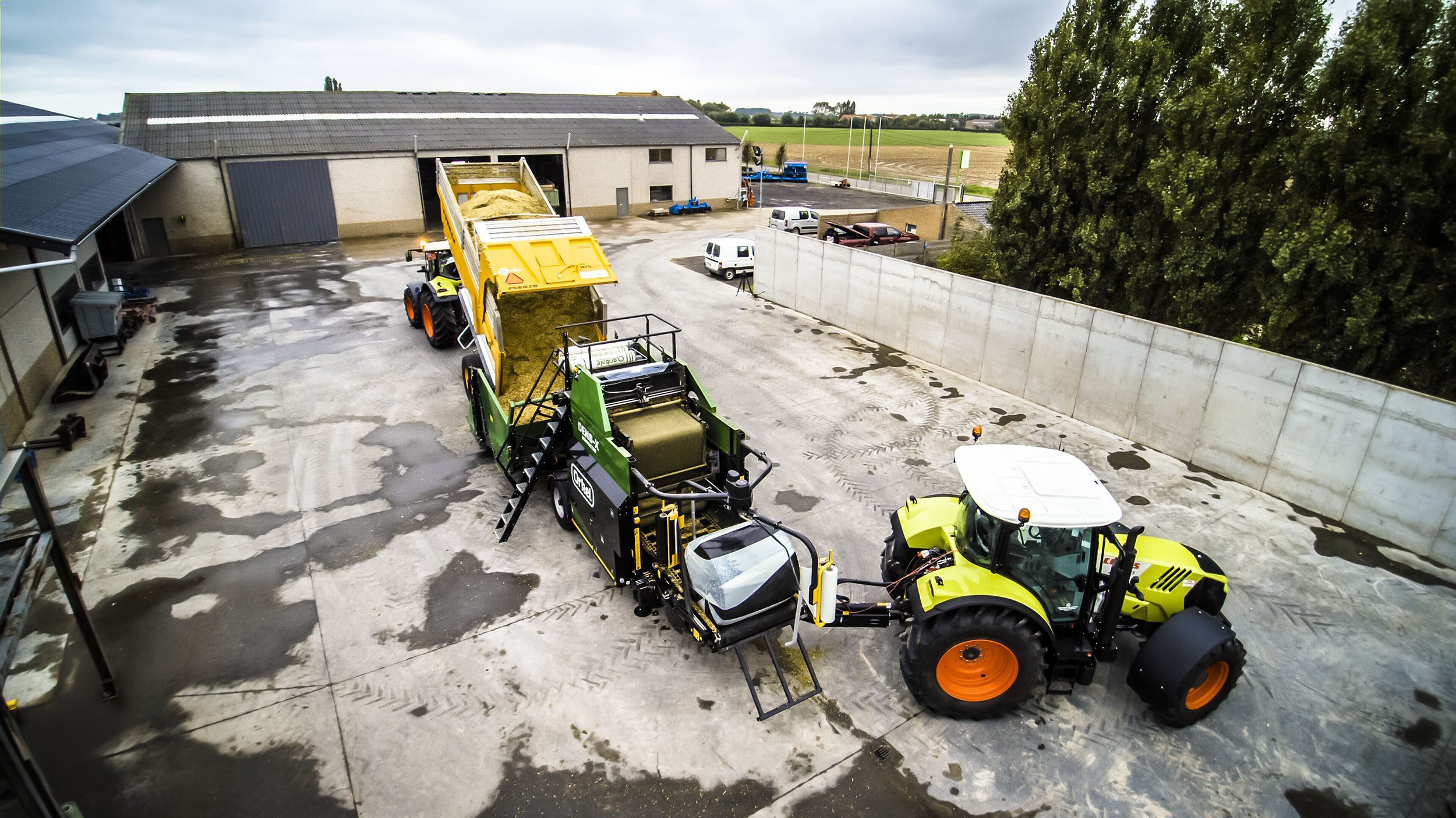 A Dens-X compactor between a tipper truck and a tractor, from a bird's-eye view.
