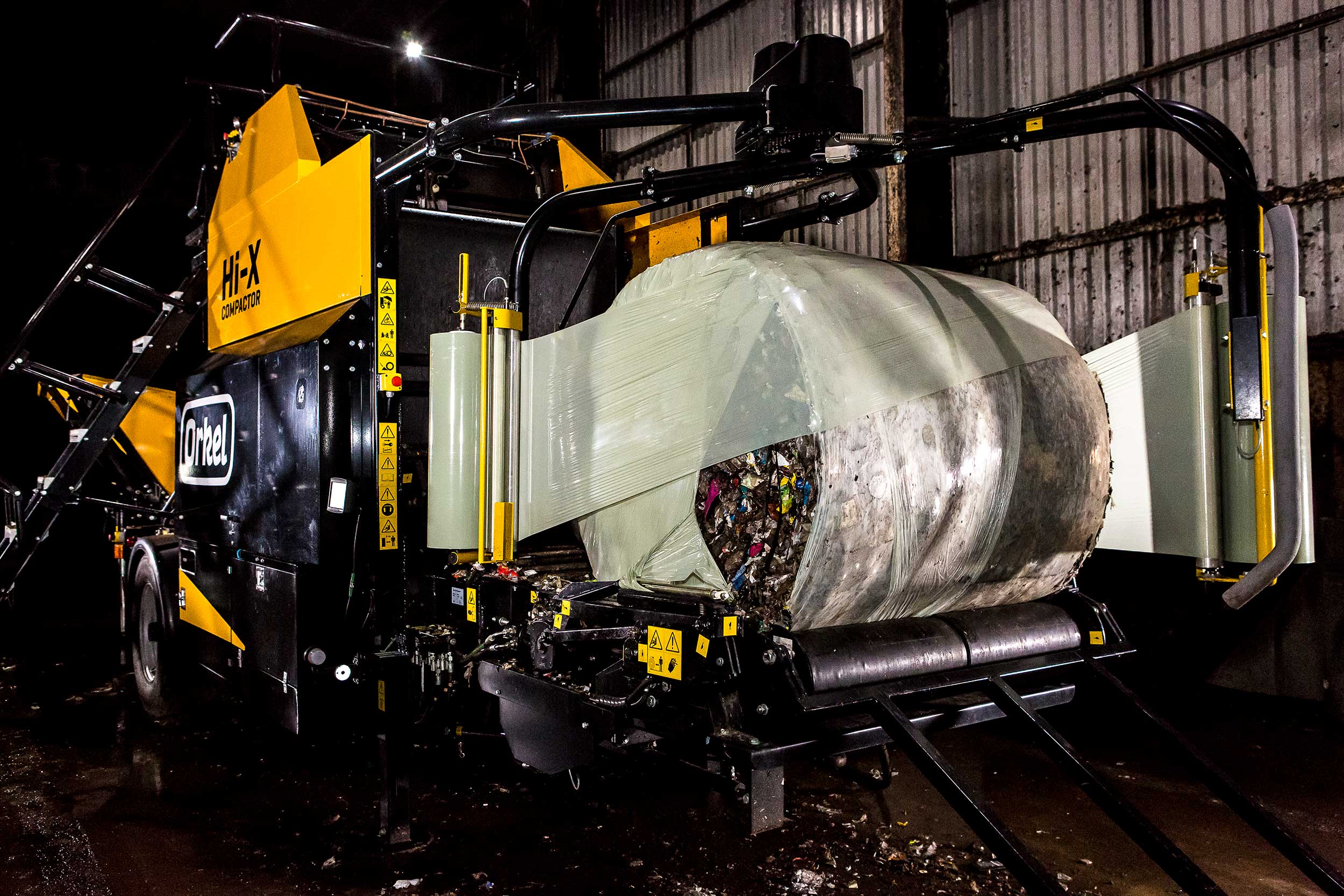 Orkel compactor in a dark warehouse, baling waste - logistics bales