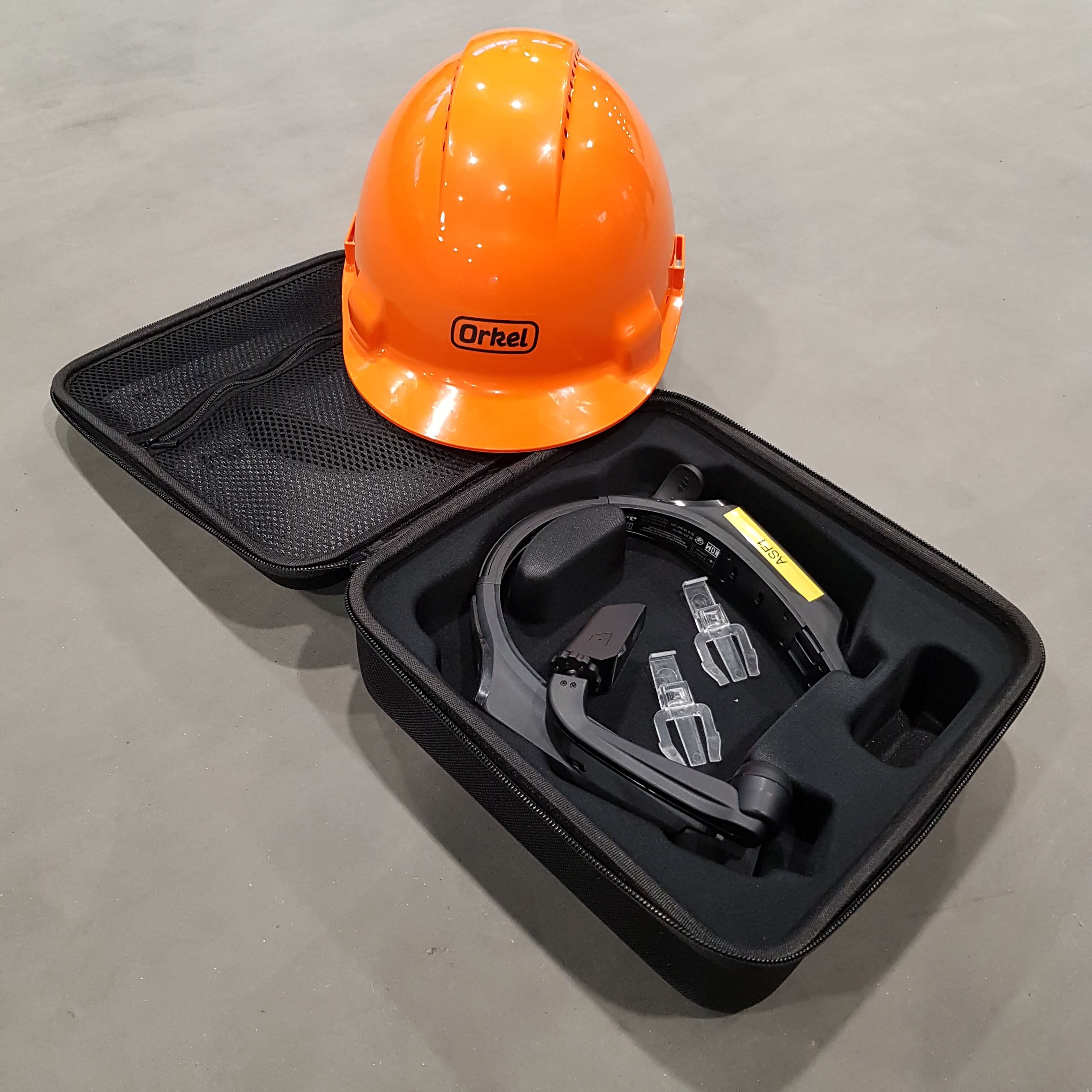 Orange hardhat lying on top of a small suitcase containing a realwear device for remote service
