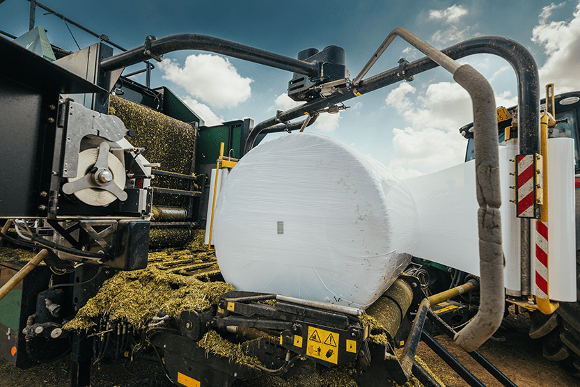 Round bale on the wrapping table, being wrapped with plastic