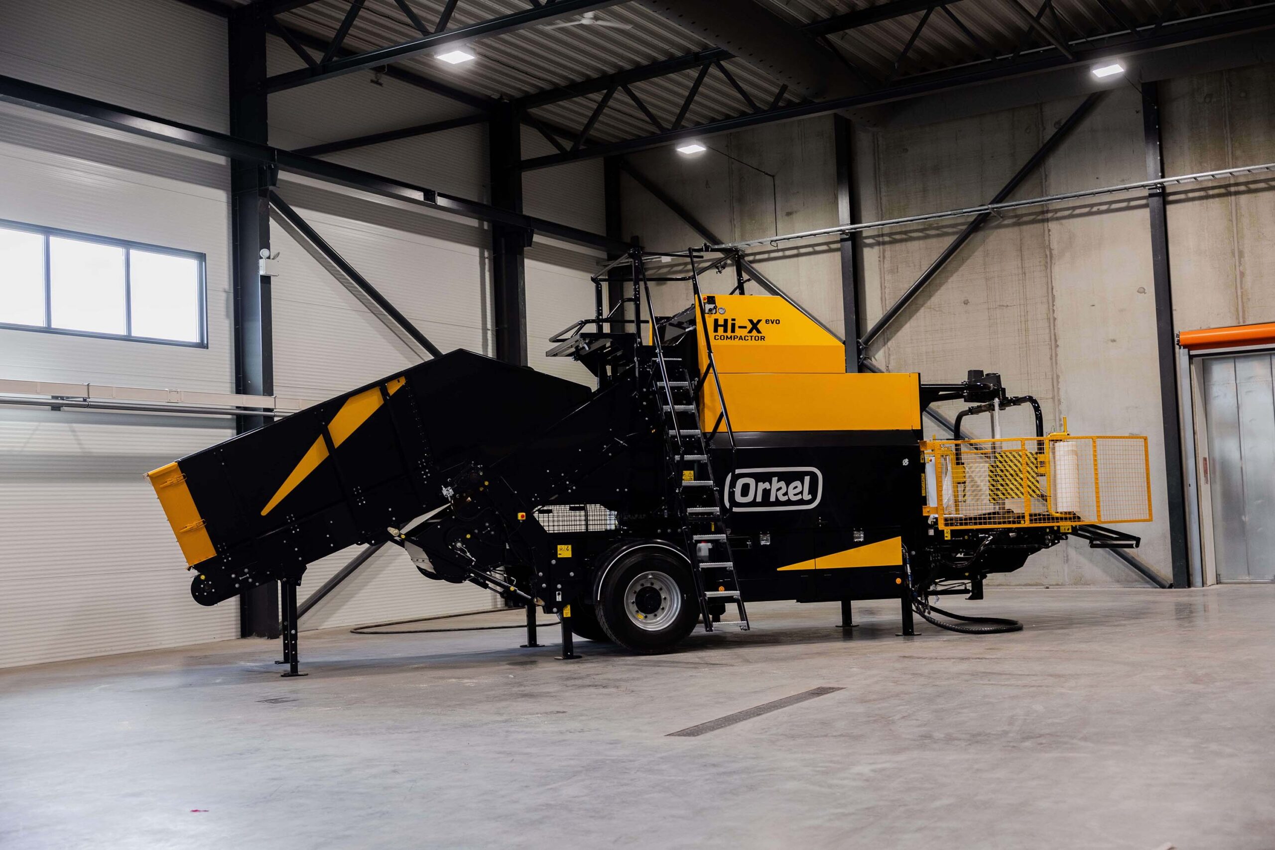 Yellow Orkel compactor standing in a factory building with concrete walls