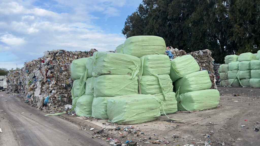 Stapel von dicht gepackten quadratischen Ballen aus Abfallmaterialien in einer Abfallverarbeitungsanlage. Die Ballen bestehen aus gepressten Recyclingmaterialien oder entsorgten Materialien.