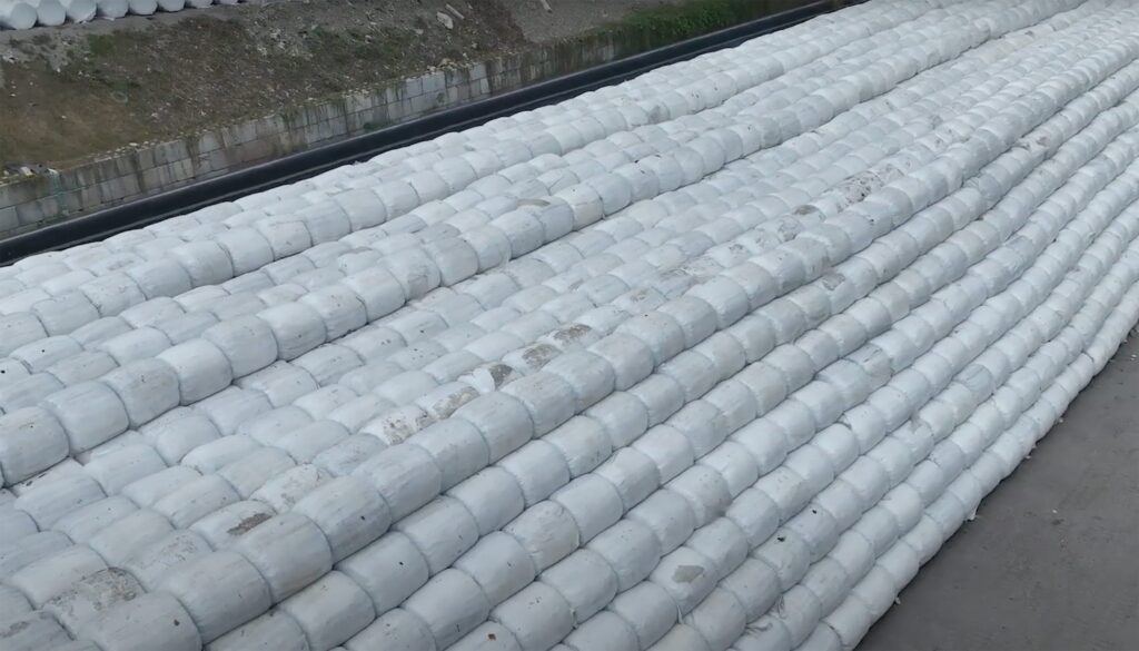 Un grand empilement de balles rondes soigneusement disposées sur un sol en béton à l'extérieur, vu d'en haut