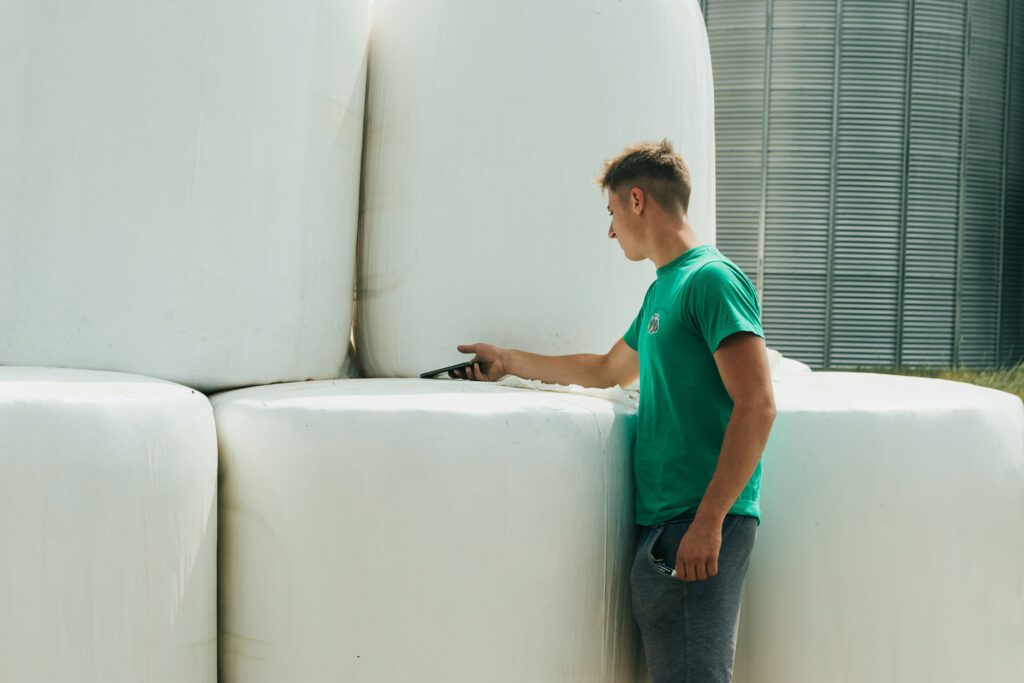 A young man using his smartphone to scan a round bale to see product declaration